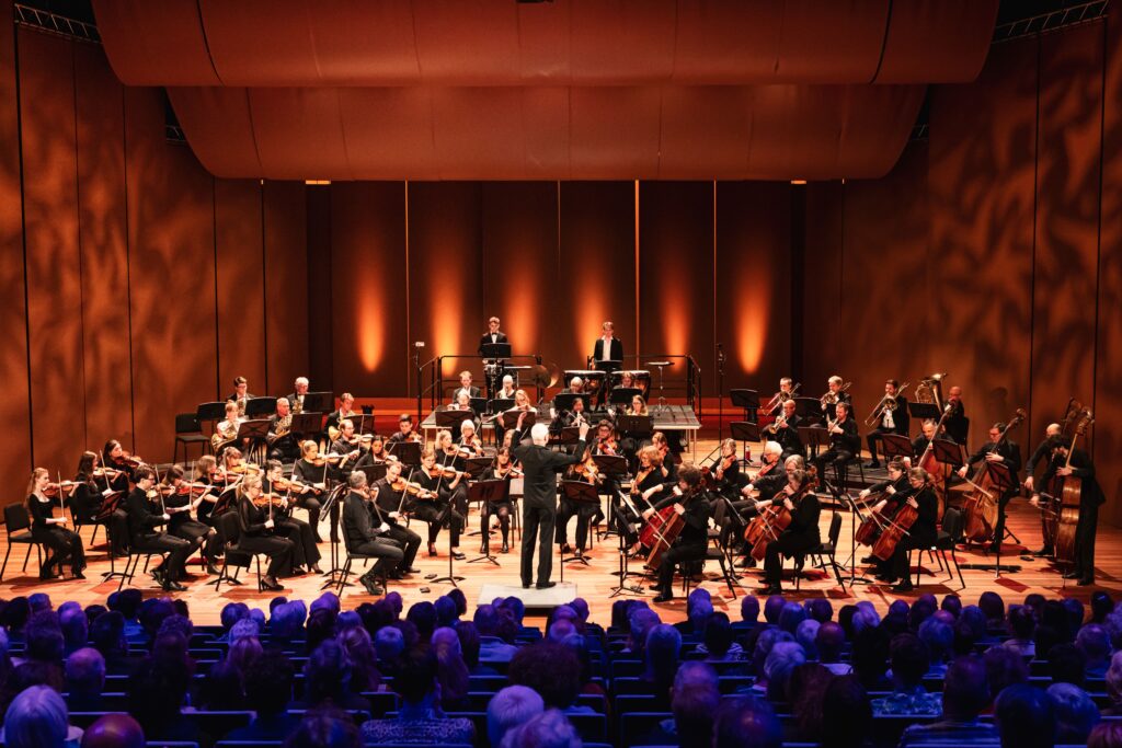 Flevolands Philharmonisch Orkest speelt op een podium met dirigent Hans Welle