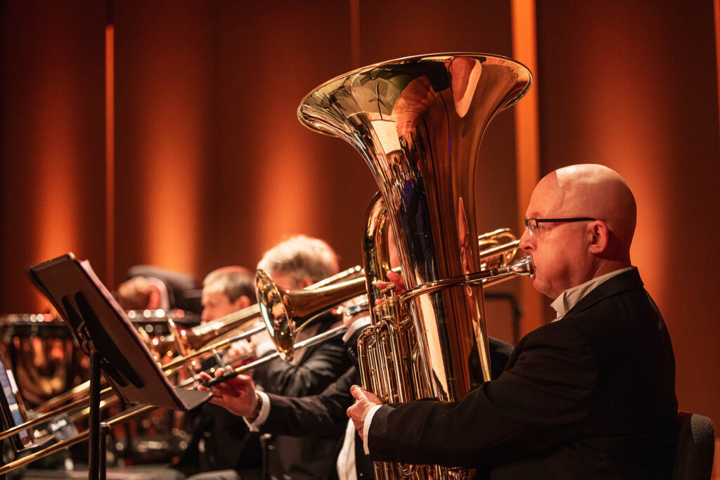 Tubaïst van het Flevolands Philharmonisch Orkest maakt muziek op een podium met dirigent Hans Welle